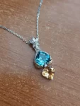 18k white gold diamond pendant. Heart cut topaz and citrine. Yellow gold sculpted hands hold blue topaz. Pendant with chain. US