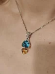 18k white and yellow gold diamond pendant. Heart cut topaz and citrine. Yellow gold sculpted hands hold blue topaz. Pendant with chain. The pendant is put on the woman. US