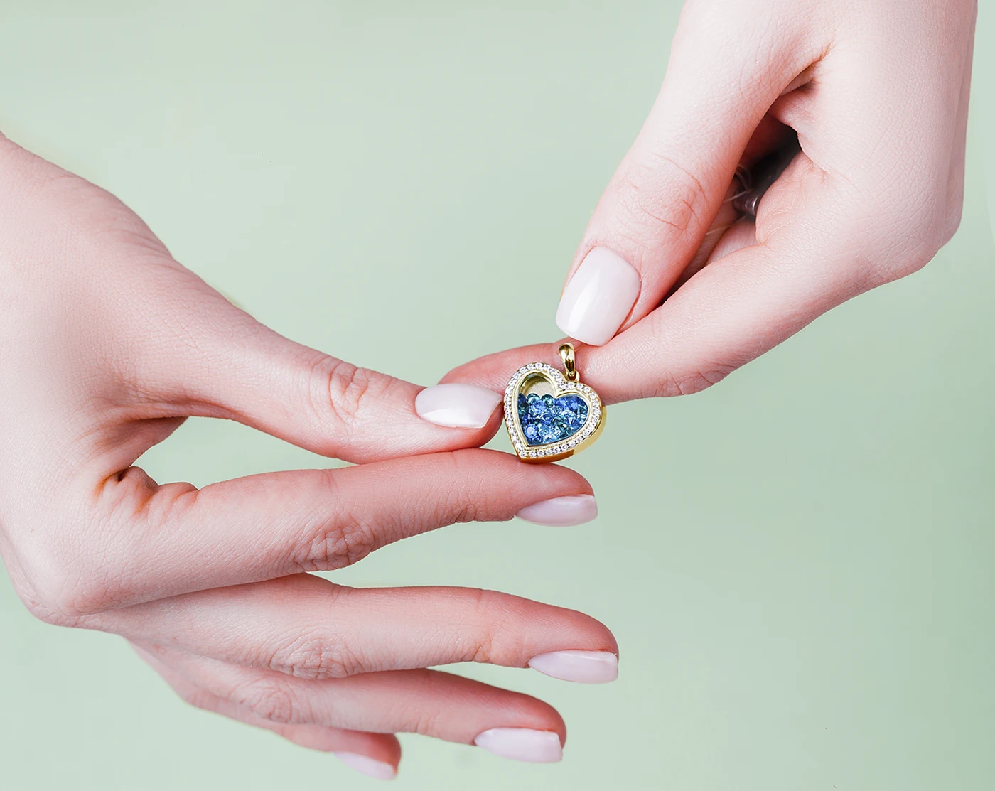 A yellow gold diamond sapphire heart-shaped pendant in a woman's hands. The Power of Connection: Insights into JCK Las Vegas 2025. News